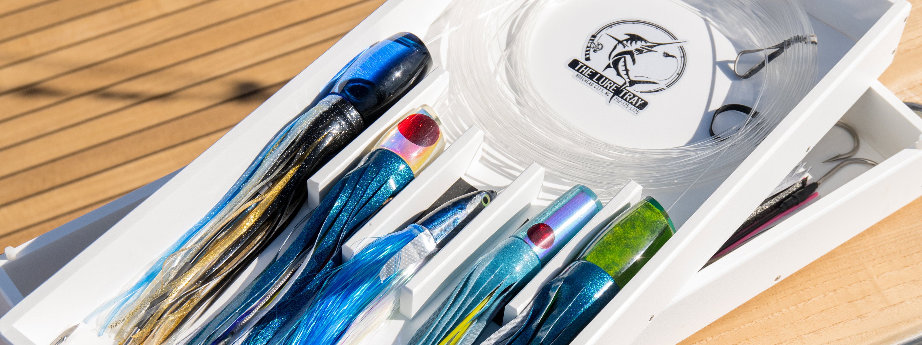 The Lure Tray lure organizer rests on the side of a boat full of lures and teasers.